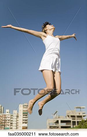 Woman jumping in midair, arms out, head back View Large Photo Image Stock Image - Woman jumping in midair, arms out, head back. Fotosearch