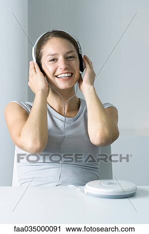 Woman listening to portable CD player, smiling at camera View Large Photo Image Stock Image - Woman listening to portable CD player, smiling at camera. Fotosearch