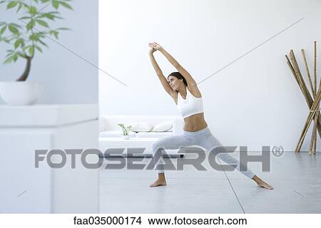Woman performing yoga pose in living room View Large Photo Image Picture - Woman performing yoga pose in living room. Fotosearch