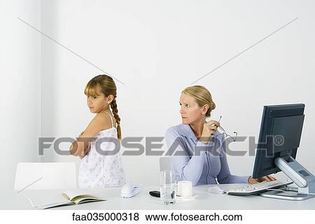 Woman sitting before computer, looking over shoulder at daughter sulking nearby View Large Photo Image Stock Photo - Woman sitting before computer, looking over shoulder at daughter sulking nearby. Fotosearch