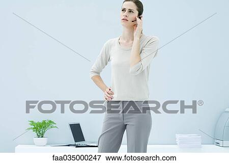 Woman standing and talking on headset, looking away View Large Photo Image Stock Photo - Woman standing and talking on headset, looking away. Fotosearch