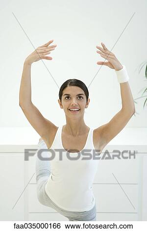Woman stretching, arms raised and one leg up behind her View Large Photo Image Stock Photograph - Woman stretching, arms raised and one leg up behind her. Fotosearch