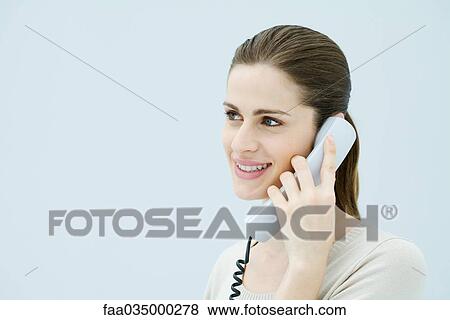 Woman talking on landline phone, looking away and smiling View Large Photo Image Stock Photo - Woman talking on landline phone, looking away and smiling. Fotosearch