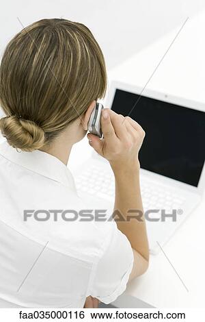 Woman using cell phone, looking at laptop, rear view View Large Photo Image Stock Photograph - Woman using cell phone, looking at laptop, rear view. Fotosearch