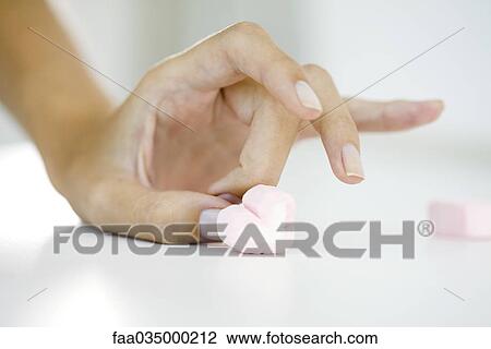 Stock Image - Woman's hand flicking marshmallow heart. Fotosearch