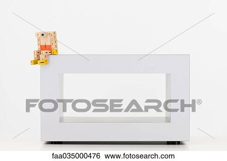 Stock Photograph - Wooden toy sitting on edge of table, head down. Fotosearch