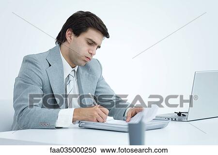 Young businessman working at desk, puffing cheeks View Large Photo Image Stock Image - Young businessman working at desk, puffing cheeks. Fotosearch