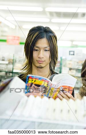 Young Japanese man reading comic book in store View Large Photo Image Stock Image - Young Japanese man reading comic book in store. Fotosearch