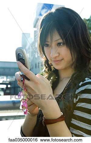 Young Japanese woman looking at cell phone View Large Photo Image Stock Photograph - Young Japanese woman looking at cell phone. Fotosearch