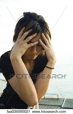 Young man standing on dock, holding head in hands View Large Photo Image Stock Image - Young man standing on dock, holding head in hands. Fotosearch