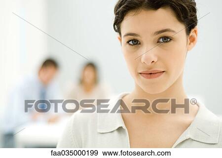 Young professional woman looking at camera, portrait, colleagues in background View Large Photo Image Stock Photo - Young professional woman looking at camera, portrait, colleagues in background. Fotosearch