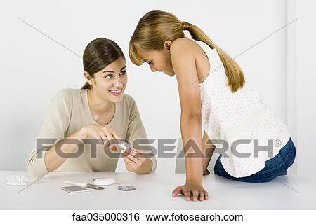 Young woman and preteen sister looking at cosmetics together, smiling View Large Photo Image Stock Photograph - Young woman and preteen sister looking at cosmetics together, smiling. Fotosearch