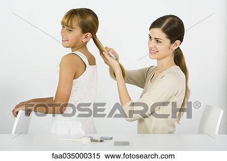 Young woman combing her younger sister's hair, side view View Large Photo Image Stock Photography - Young woman combing her younger sister's hair, side view. Fotosearch