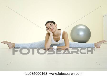 Young woman doing splits on the ground, leaning on elbow, eyes closed View Large Photo Image Stock Photo - Young woman doing splits on the ground, leaning on elbow, eyes closed. Fotosearch