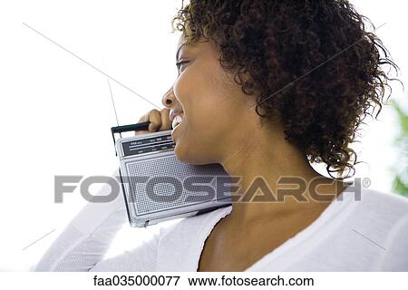Young woman holding radio on shoulder, smiling, profile View Large Photo Image Stock Photo - Young woman holding radio on shoulder, smiling, profile. Fotosearch