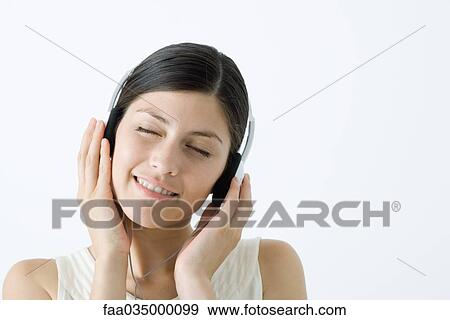 Young woman listening to headphones, smiling, eyes closed View Large Photo Image Stock Photo - Young woman listening to headphones, smiling, eyes closed. Fotosearch