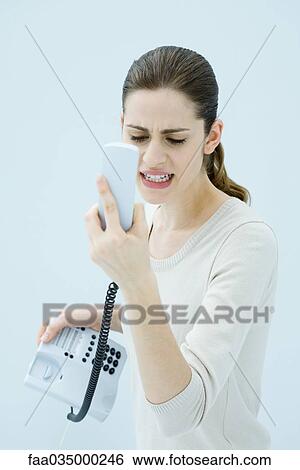 Young woman shouting at landline phone, receiver in hand View Large Photo Image Stock Photograph - Young woman shouting at landline phone, receiver in hand. Fotosearch