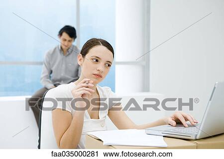 Young woman sitting at makeshift desk, using laptop computer View Large Photo Image Stock Image - Young woman sitting at makeshift desk, using laptop computer. Fotosearch