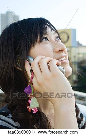 Young woman talking on cell phone, looking up, close-up View Large Photo Image Stock Photo - Young woman talking on cell phone, looking up, close-up. Fotosearch