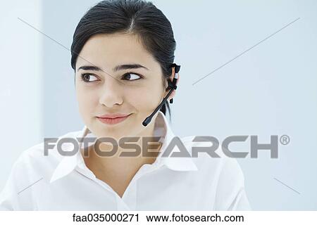 Young woman wearing headset, looking away, portrait View Large Photo Image Stock Image - Young woman wearing headset, looking away, portrait. Fotosearch