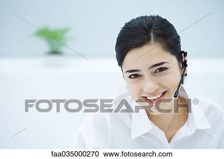 Young woman wearing headset, smiling at camera, portrait View Large Photo Image Stock Image - Young woman wearing headset, smiling at camera, portrait. Fotosearch