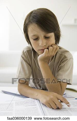 Boy reading homework and listening to earphones View Large Photo Image Stock Photo - Boy reading homework and listening to earphones. Fotosearch