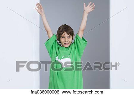 Boy wearing oversized tee-shirt with watering can printed on it, arms raised in the air, smiling View Large Photo Image Stock Photograph - Boy wearing oversized tee-shirt with watering can printed on it, arms raised in the air, smiling. Fotosearch