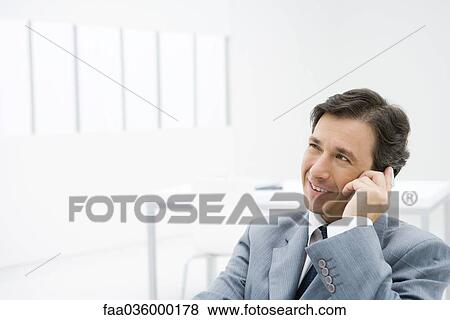 Businessman talking on cell phone, looking away View Large Photo Image Stock Photo - Businessman talking on cell phone, looking away. Fotosearch