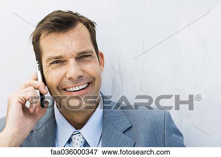 Businessman using cell phone, smiling at camera View Large Photo Image Stock Photo - Businessman using cell phone, smiling at camera. Fotosearch