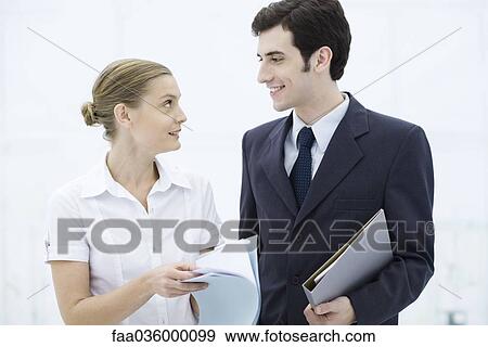 Colleagues looking at each other, holding folders View Large Photo Image Stock Photo - Colleagues looking at each other, holding folders. Fotosearch