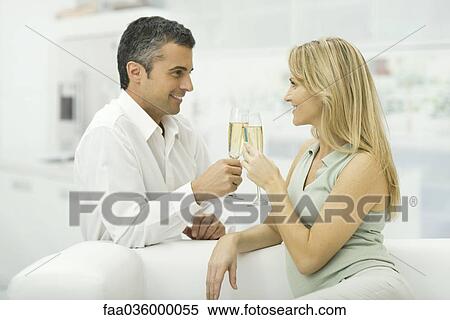 Couple clinking champagne glasses, smiling at each other View Large Photo Image Stock Photography - Couple clinking champagne glasses, smiling at each other. Fotosearch