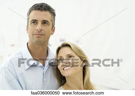 Couple smiling, looking up, portrait View Large Photo Image Stock Image - Couple smiling, looking up, portrait. Fotosearch