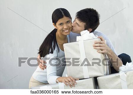 Couple standing behind stack of large gift boxes, man kissing woman on cheek View Large Photo Image Stock Photography - Couple standing behind stack of large gift boxes, man kissing woman on cheek. Fotosearch