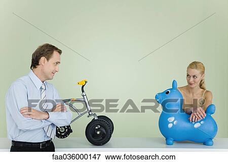 Couple standing by toys, looking at each other, man's arms folded View Large Photo Image Stock Photo - Couple standing by toys, looking at each other, man's arms folded. Fotosearch