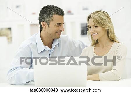 Couple using laptop computer together, smiling View Large Photo Image Stock Photo - Couple using laptop computer together, smiling. Fotosearch