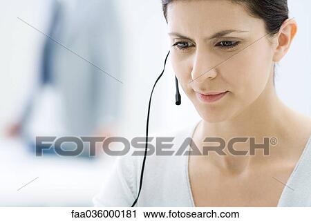 Stock Image - Customer service representative wearing headset, looking down. Fotosearch