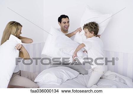 Family having pillow fight on bed View Large Photo Image Picture - Family having pillow fight on bed. Fotosearch