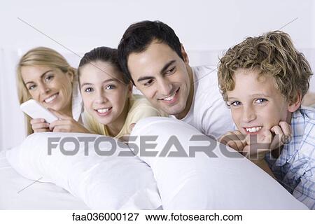 Family relaxing in bed together, smiling at camera, father looking at son View Large Photo Image Stock Photo - Family relaxing in bed together, smiling at camera, father looking at son. Fotosearch