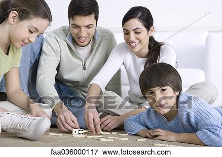 Family seated on floor playing dominoes together, boy smiling at camera View Large Photo Image Stock Photo - Family seated on floor playing dominoes together, boy smiling at camera. Fotosearch