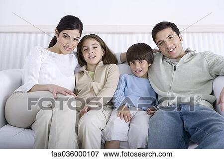 Stock Photo - Family sitting together on sofa, smiling at camera, portrait. Fotosearch