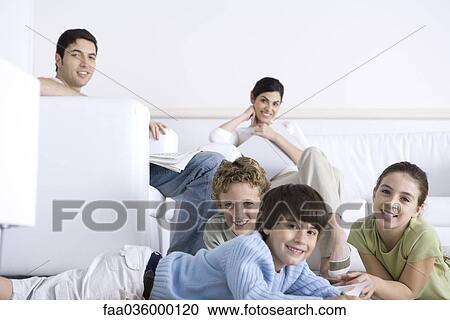 Family together in living room, parents sitting on sofa, children lying on the floor, smiling at camera View Large Photo Image Stock Image - Family together in living room, parents sitting on sofa, children lying on the floor, smiling at camera. Fotosearch