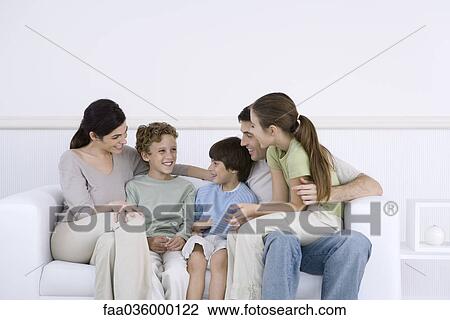 Family with three children sitting together on sofa, talking View Large Photo Image Stock Image - Family with three children sitting together on sofa, talking. Fotosearch