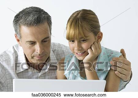 Father and daughter looking at laptop computer together, man's arm around girl's shoulder View Large Photo Image Stock Photography - Father and daughter looking at laptop computer together, man's arm around girl's shoulder. Fotosearch