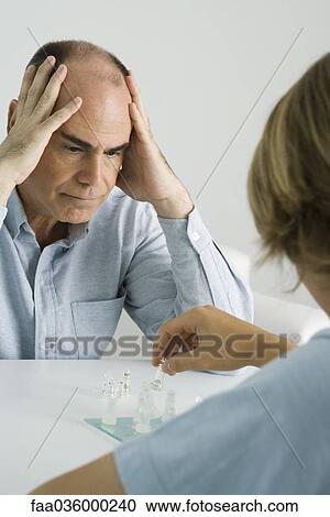Father and son playing chess, man holding head with both hands View Large Photo Image Stock Image - Father and son playing chess, man holding head with both hands. Fotosearch