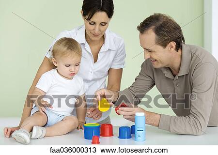 Father showing toddler plastic toys, mother watching View Large Photo Image Stock Image - Father showing toddler plastic toys, mother watching. Fotosearch