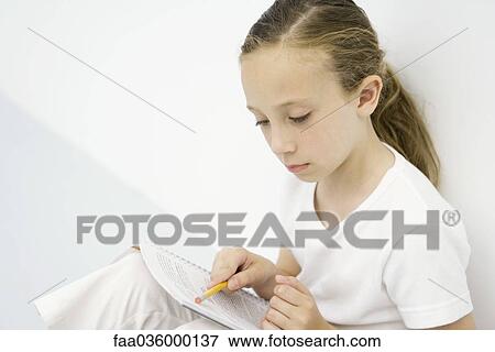 Girl leaning against wall, reading notebook, holding pencil View Large Photo Image Stock Photo - Girl leaning against wall, reading notebook, holding pencil. Fotosearch