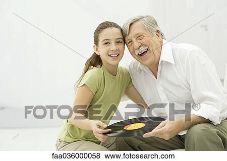 Grandfather and granddaughter holding record album together, smiling, portrait View Large Photo Image Stock Photo - Grandfather and granddaughter holding record album together, smiling, portrait. Fotosearch