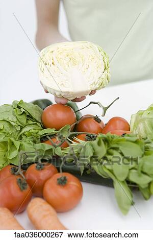 Hand holding half head of lettuce, assorted fresh vegetables in foreground View Large Photo Image Stock Photo - Hand holding half head of lettuce, assorted fresh vegetables in foreground. Fotosearch