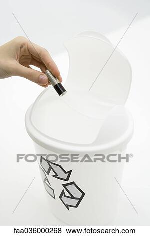Stock Photo - Hand placing battery into recycling bin, close-up. Fotosearch