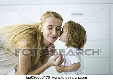 Little girl kissing mother's cheek, woman holding a tiny heart, eyes closed View Large Photo Image Stock Image - Little girl kissing mother's cheek, woman holding a tiny heart, eyes closed. Fotosearch